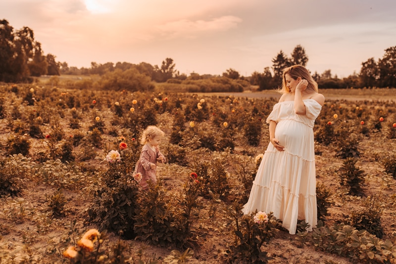 Family Photographer, An expectant mother walks through flower fields with her young daughter