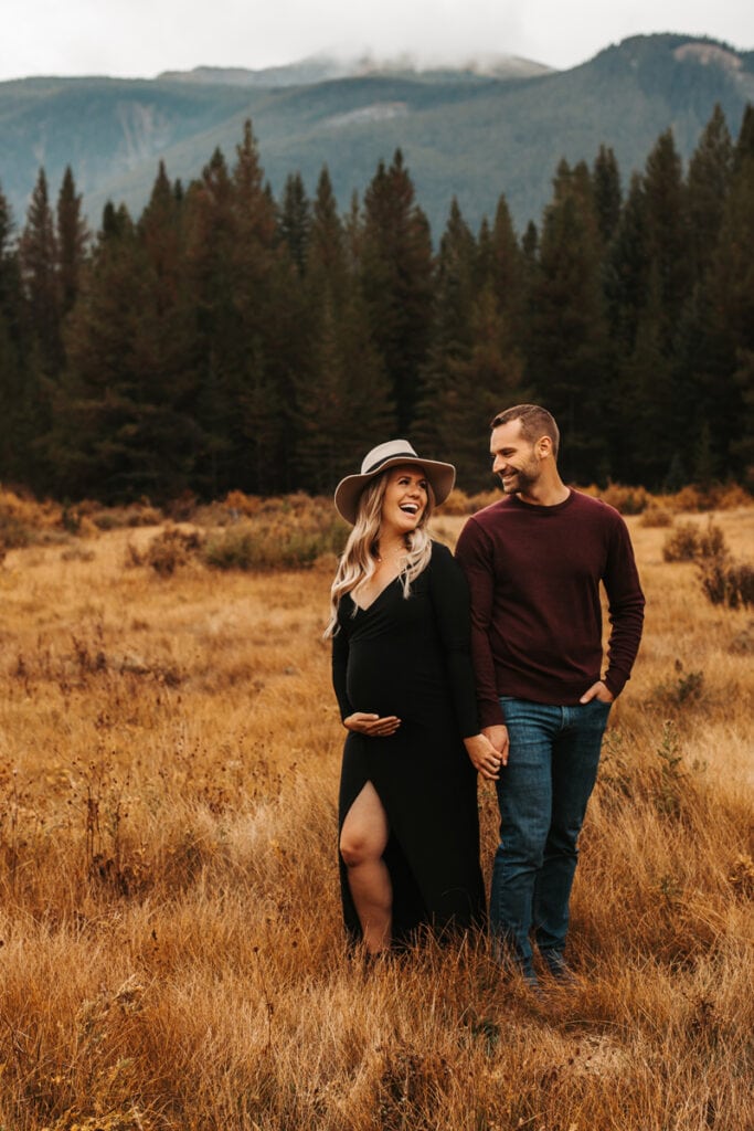 Family Photographer, Man and woman walk together in dry meadows near the forest, she is pregnant